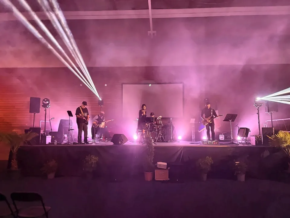 Concert sur scène dans une salle embrumée, faisceaux blancs