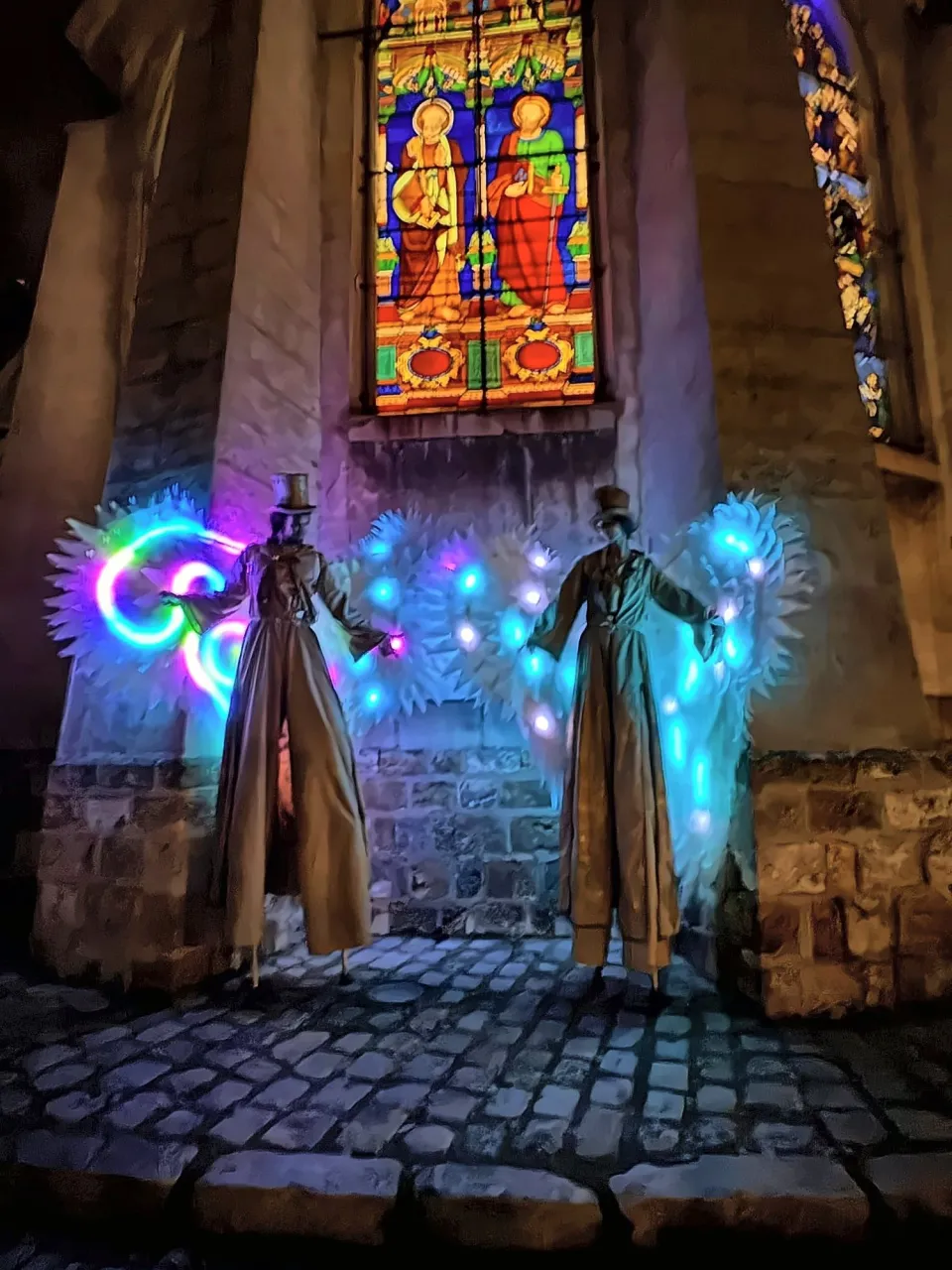 Échassiers lumineux devant les vitraux d'une église, de nuit