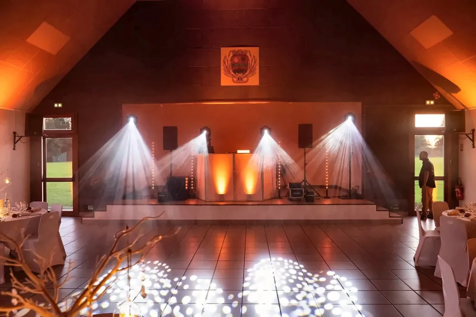 Salle de réception préparée : quatre lyres, scène éclairée et motifs lumineux sur la piste