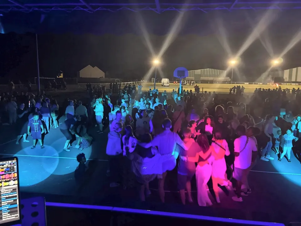Fête de plein air de nuit : la foule danse sous les projecteurs colorés